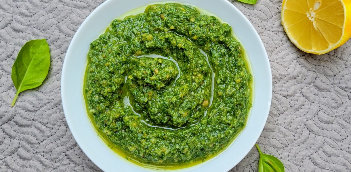 Pesto in white bowl with lemon and basil