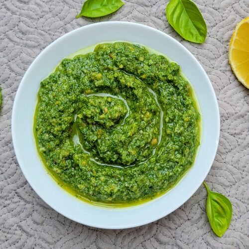 Pesto in white bowl with lemon and basil